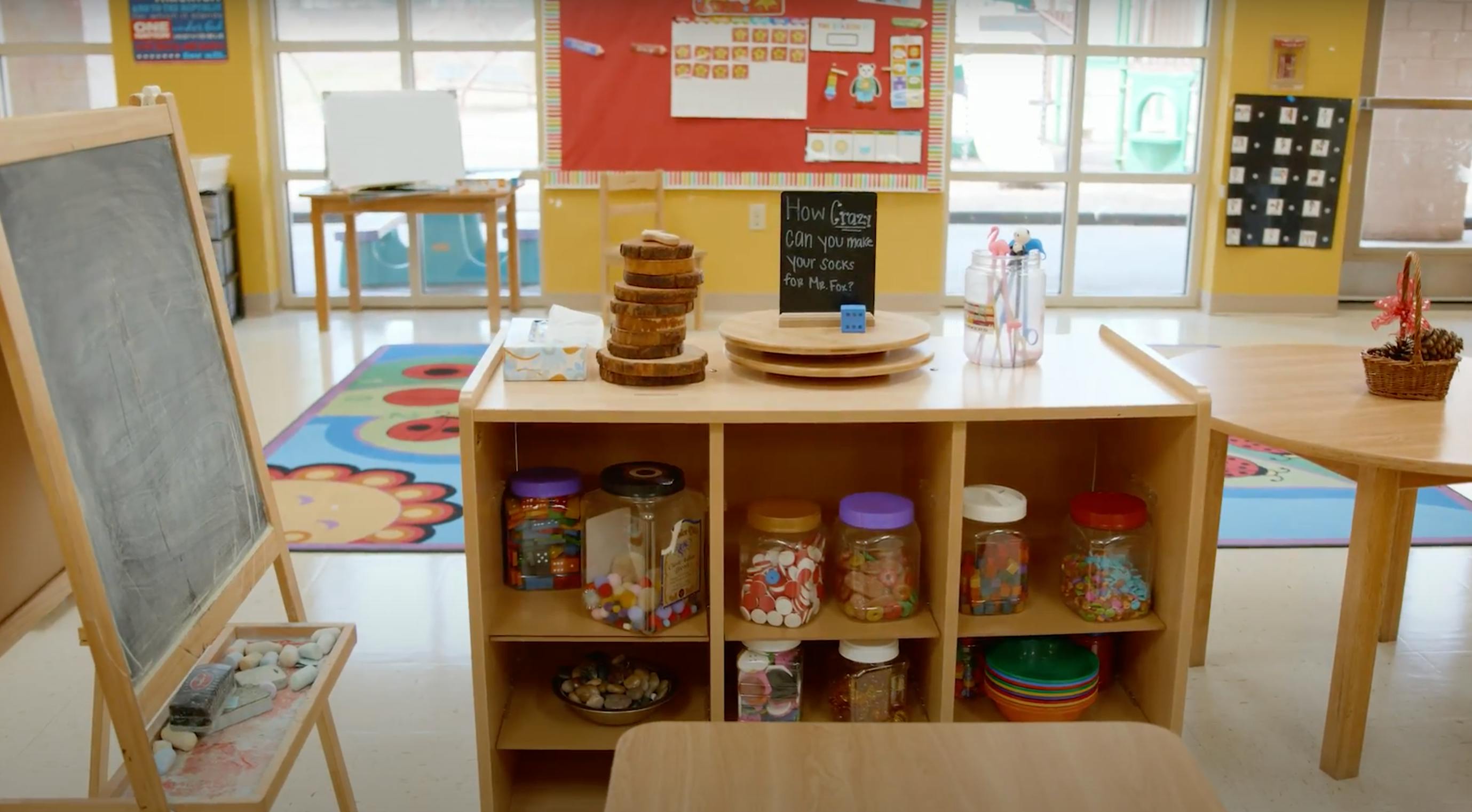 Classroom with a chalkboard, wooden shelves, and tables