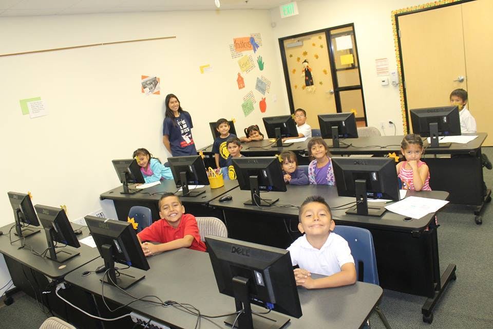 Children and an adult in a classroom with computers