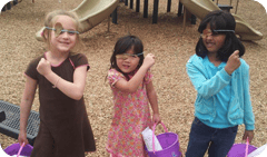 Three children wearing sunglasses and holding baskets on to purple bags