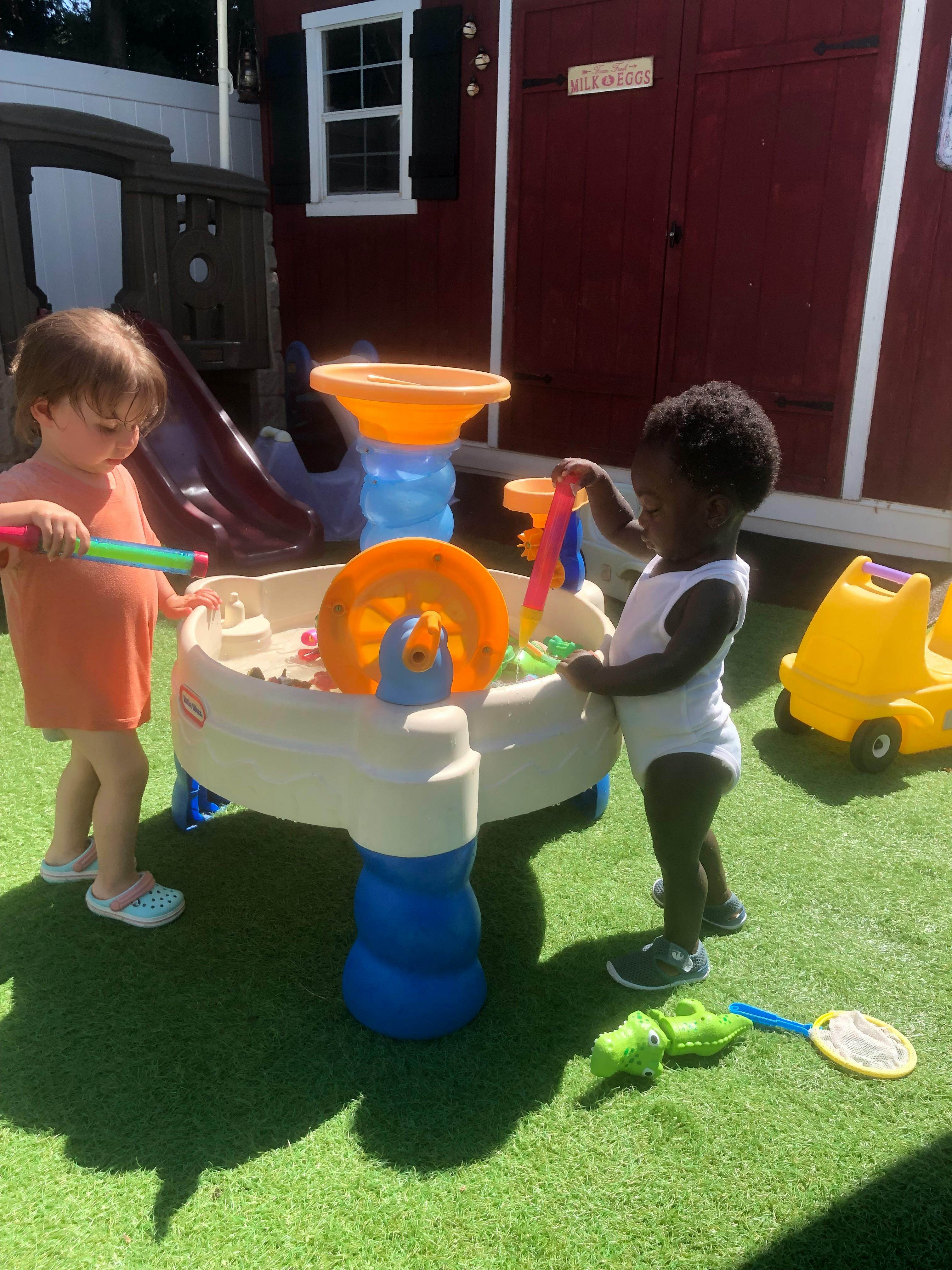 Two children playing at a water table outdoors