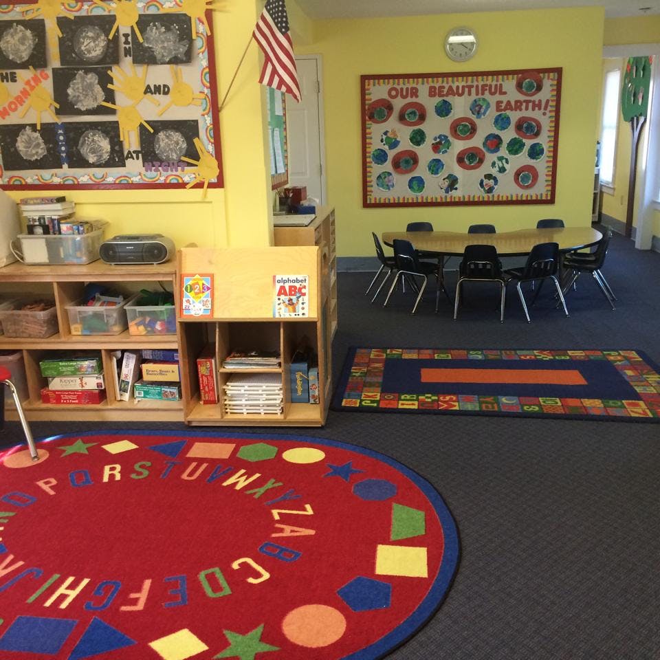Classroom with alphabet rug, shelves, and a table with chairs