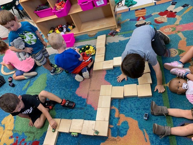 Children playing with wooden blocks on a colorful rug