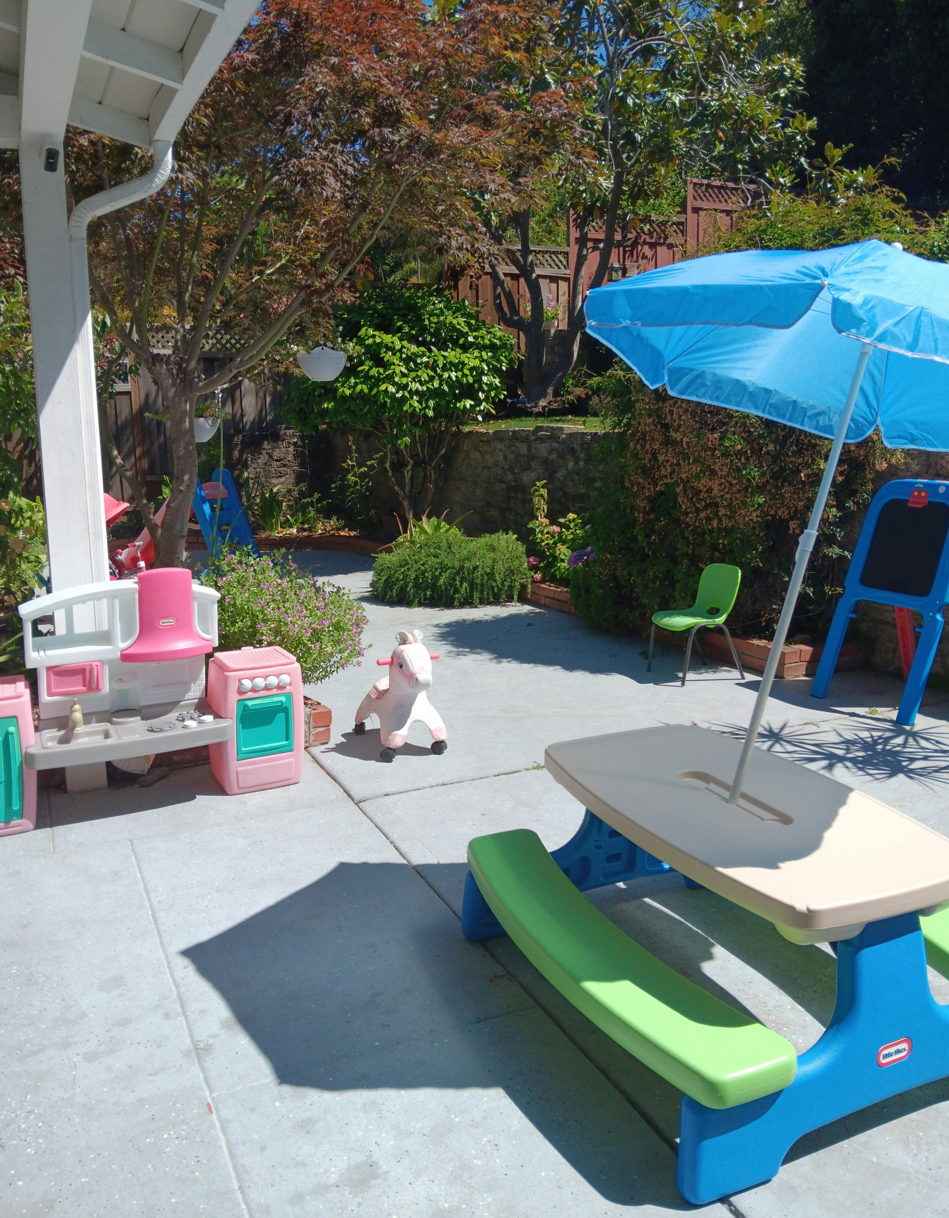 Outdoor patio with children's play kitchen, picnic table, and umbrella