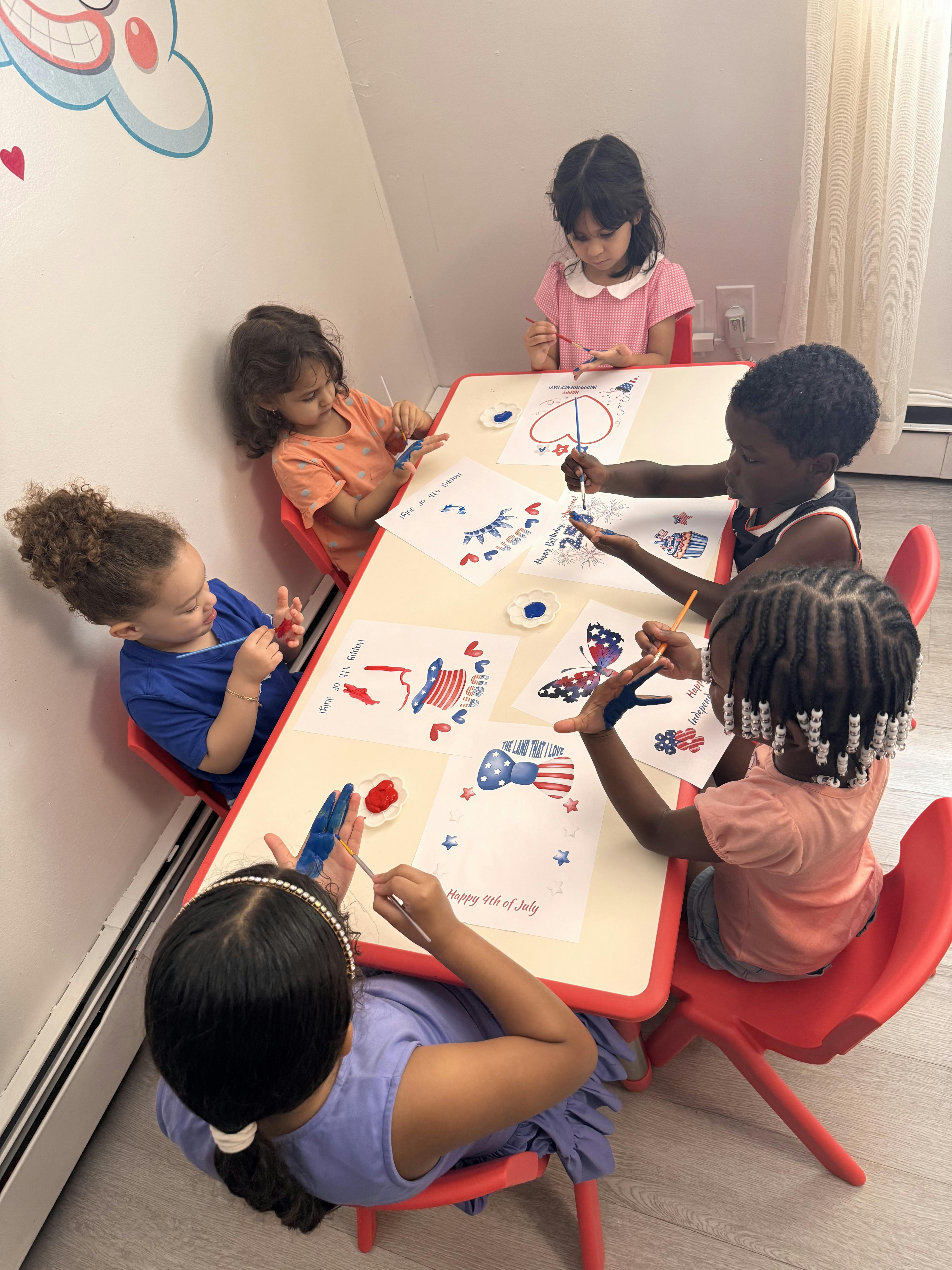 Group of children painting patriotic art projects at a table