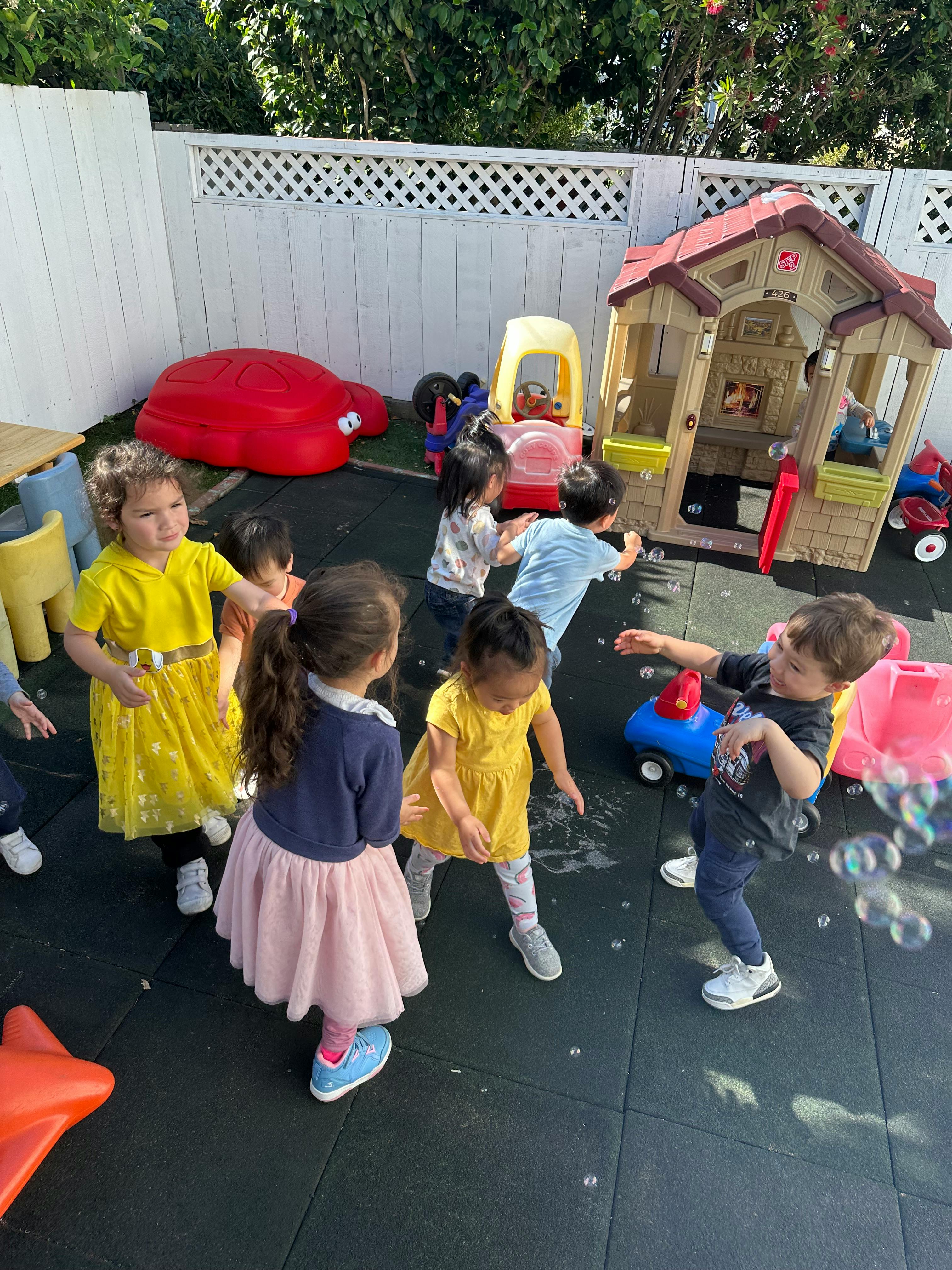 Children playing outdoors with bubbles and toys
