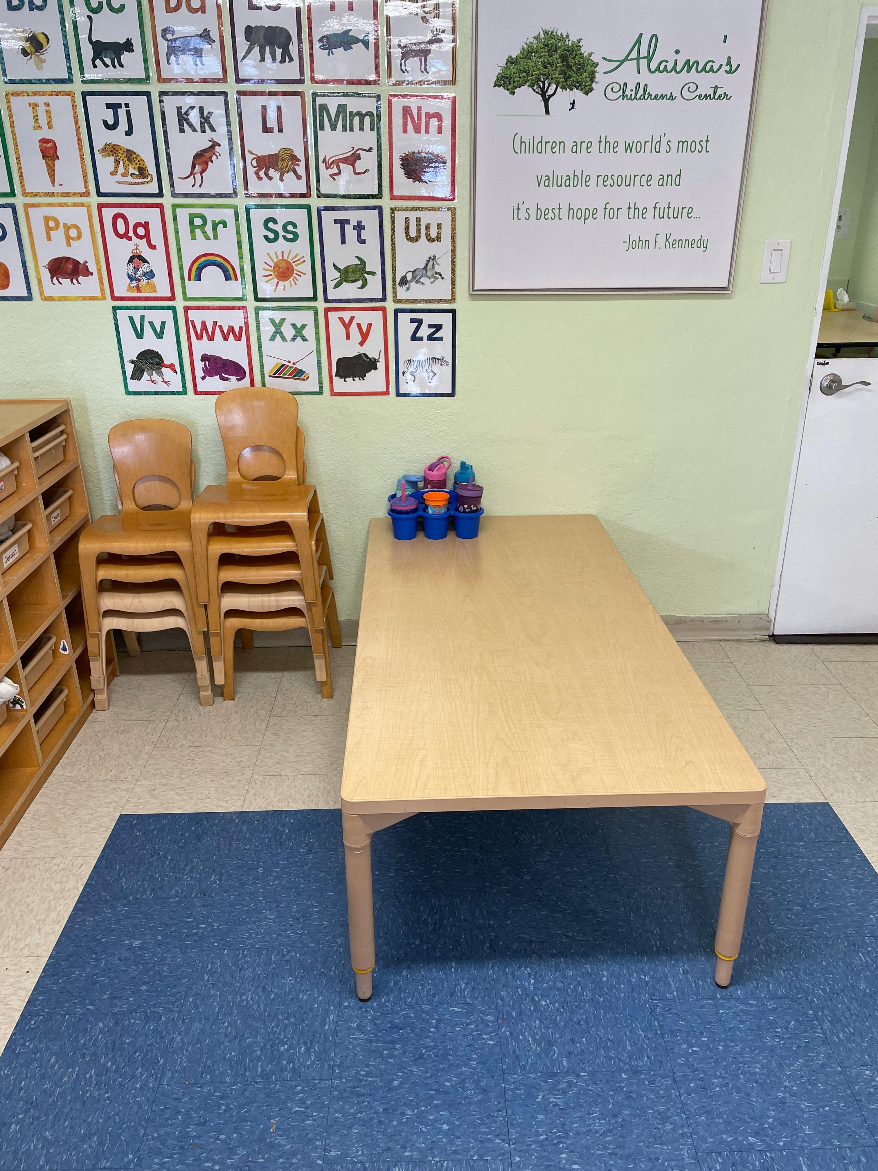 Classroom with alphabet charts, small table, and stacked chairs