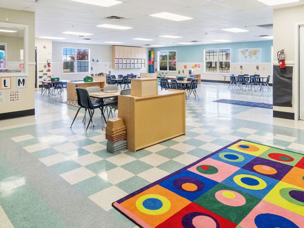Empty classroom with tables, chairs, and colorful rug