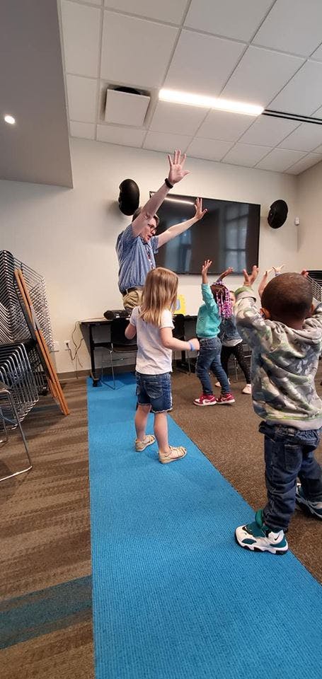 Adult and children with arms raised in a room