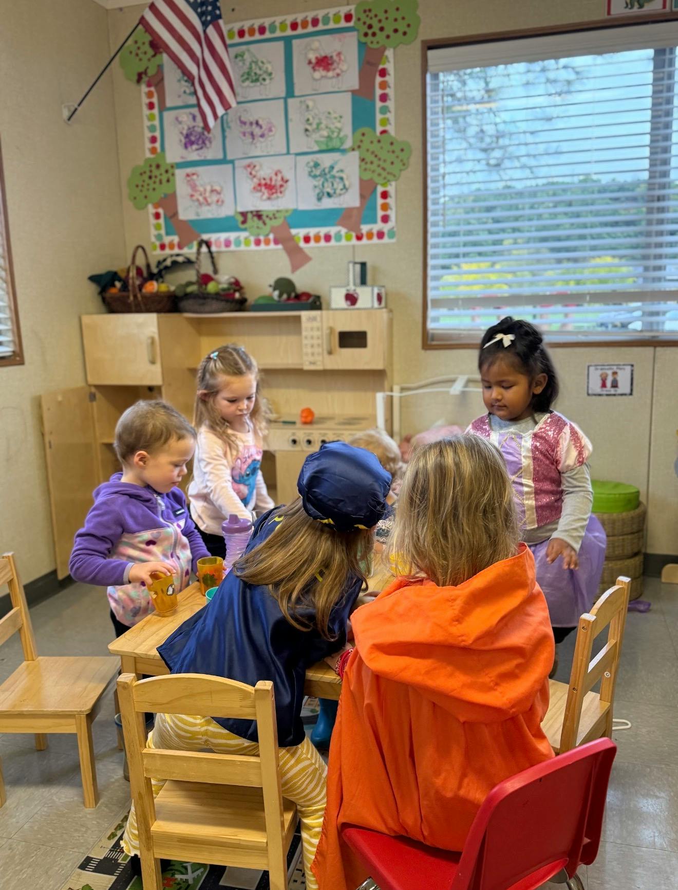 Group of children playing together around a small table in a classroom