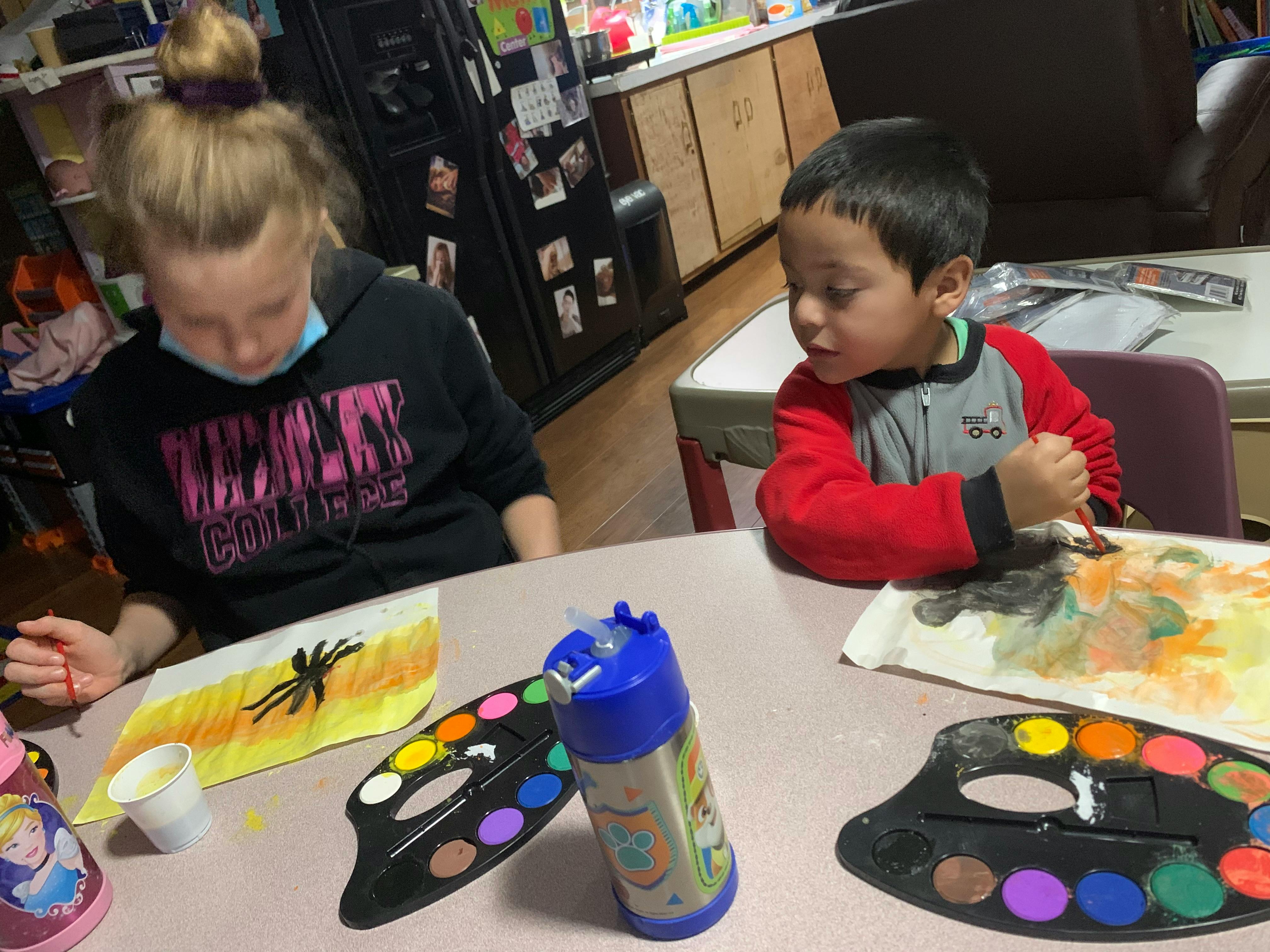 Two children painting at a table