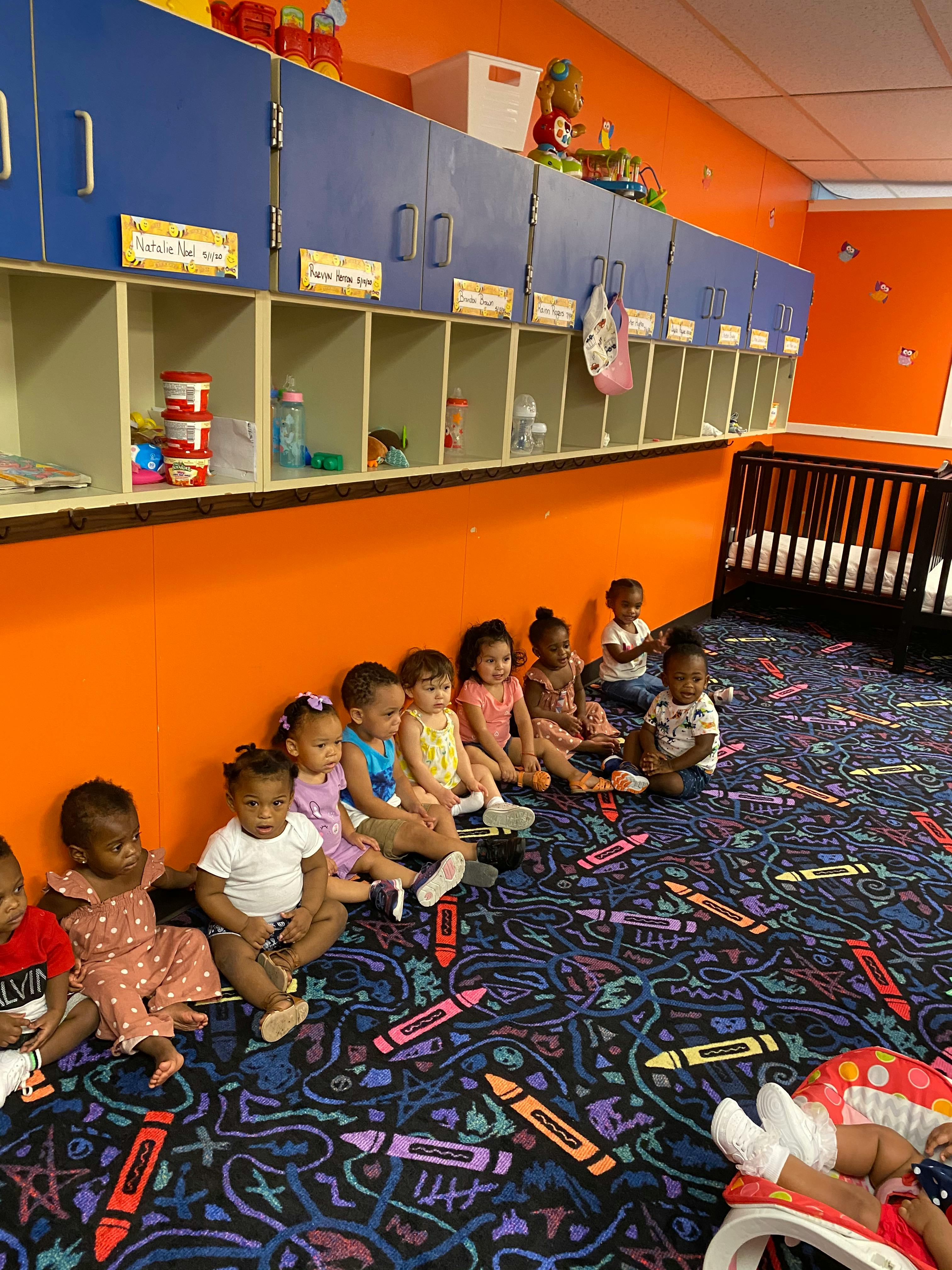 Group of children sitting on a crayon-patterned carpet
