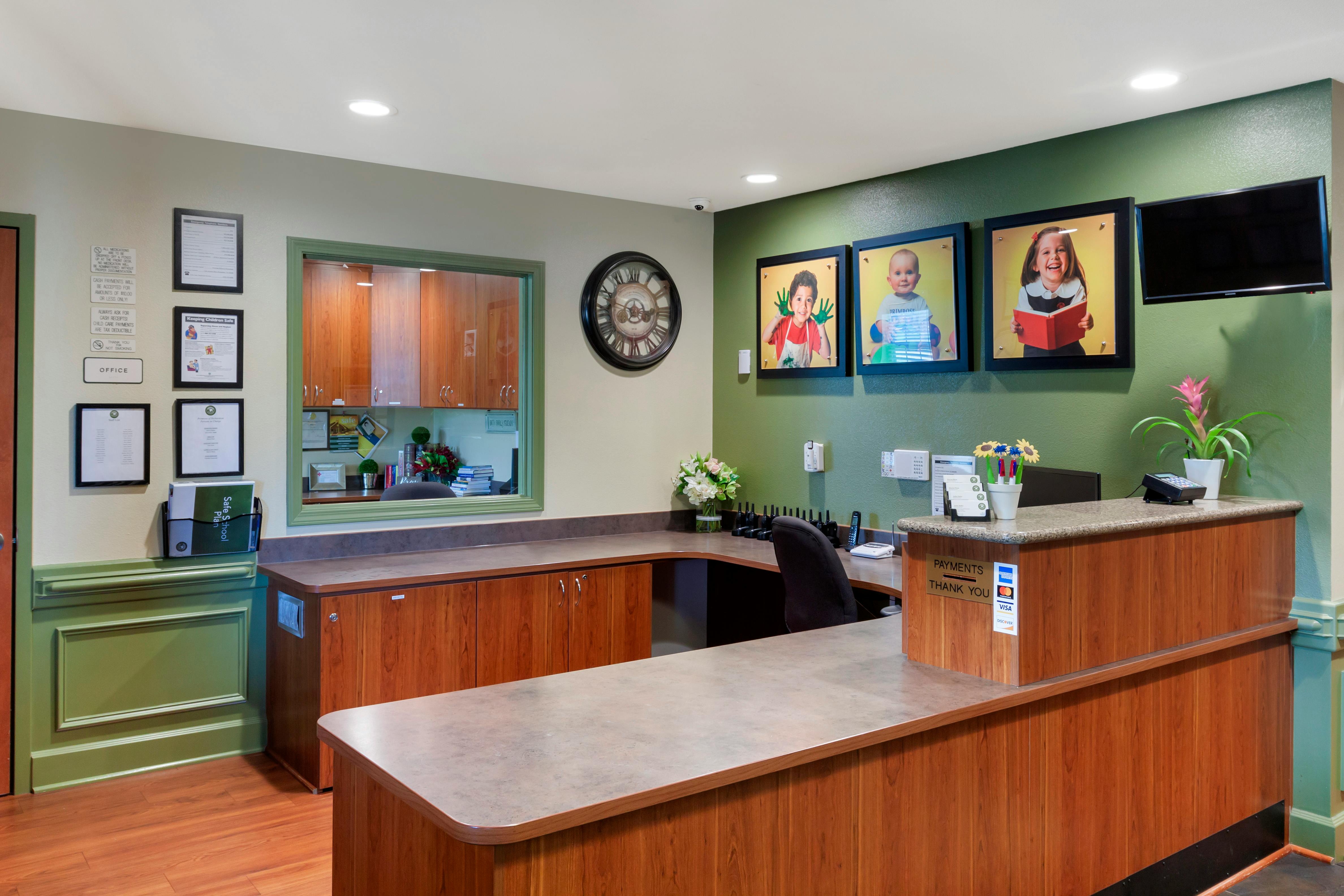 Reception desk with child artwork and a payment sign