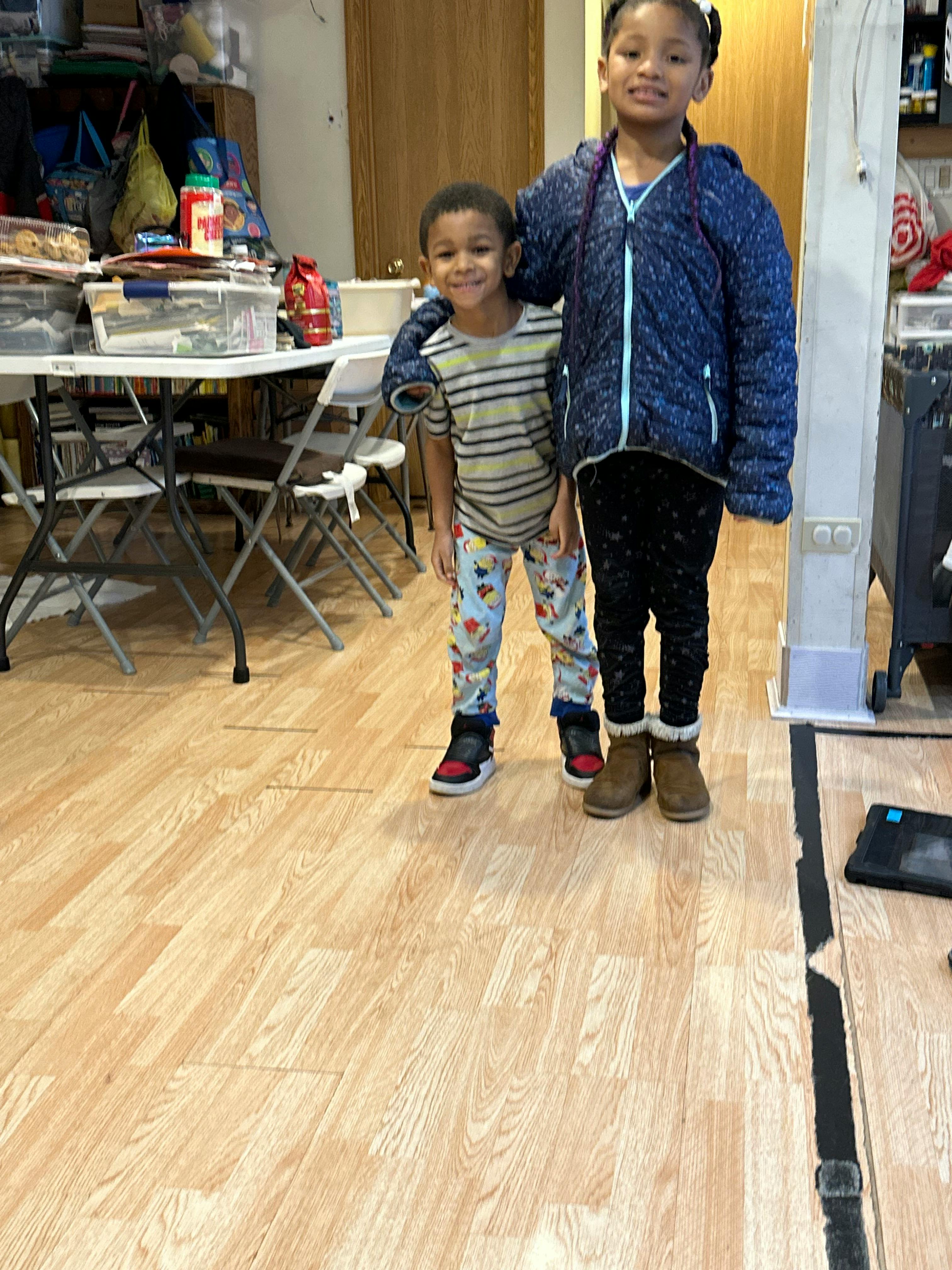 Two children standing together, one with an arm around the other