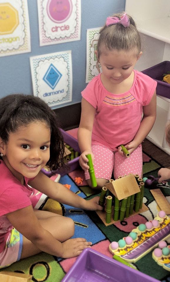 Two children playing with building blocks on a colorful rug