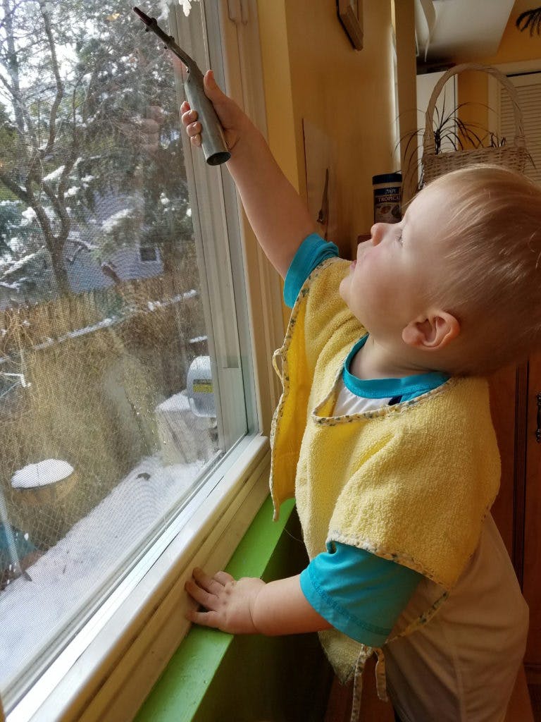 Child looking out a window at a snowy outdoor scene