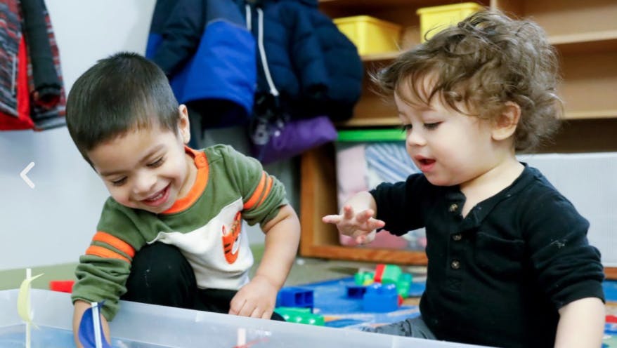 Two children playing with toys in a container