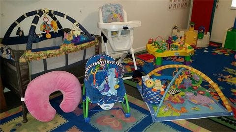 Baby play area with a crib, bouncer, play mat, and high chair