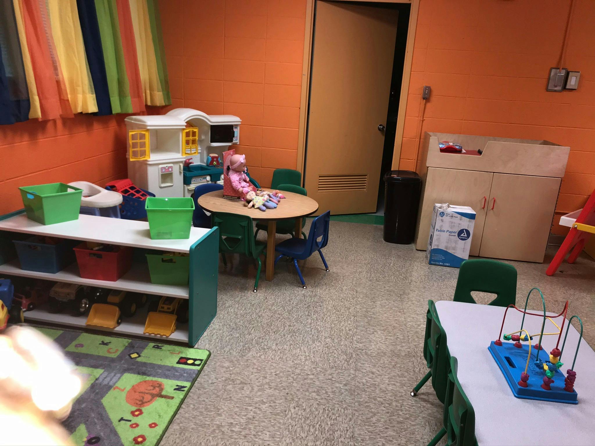 Playroom with small tables and chairs, toy kitchen, and storage shelves
