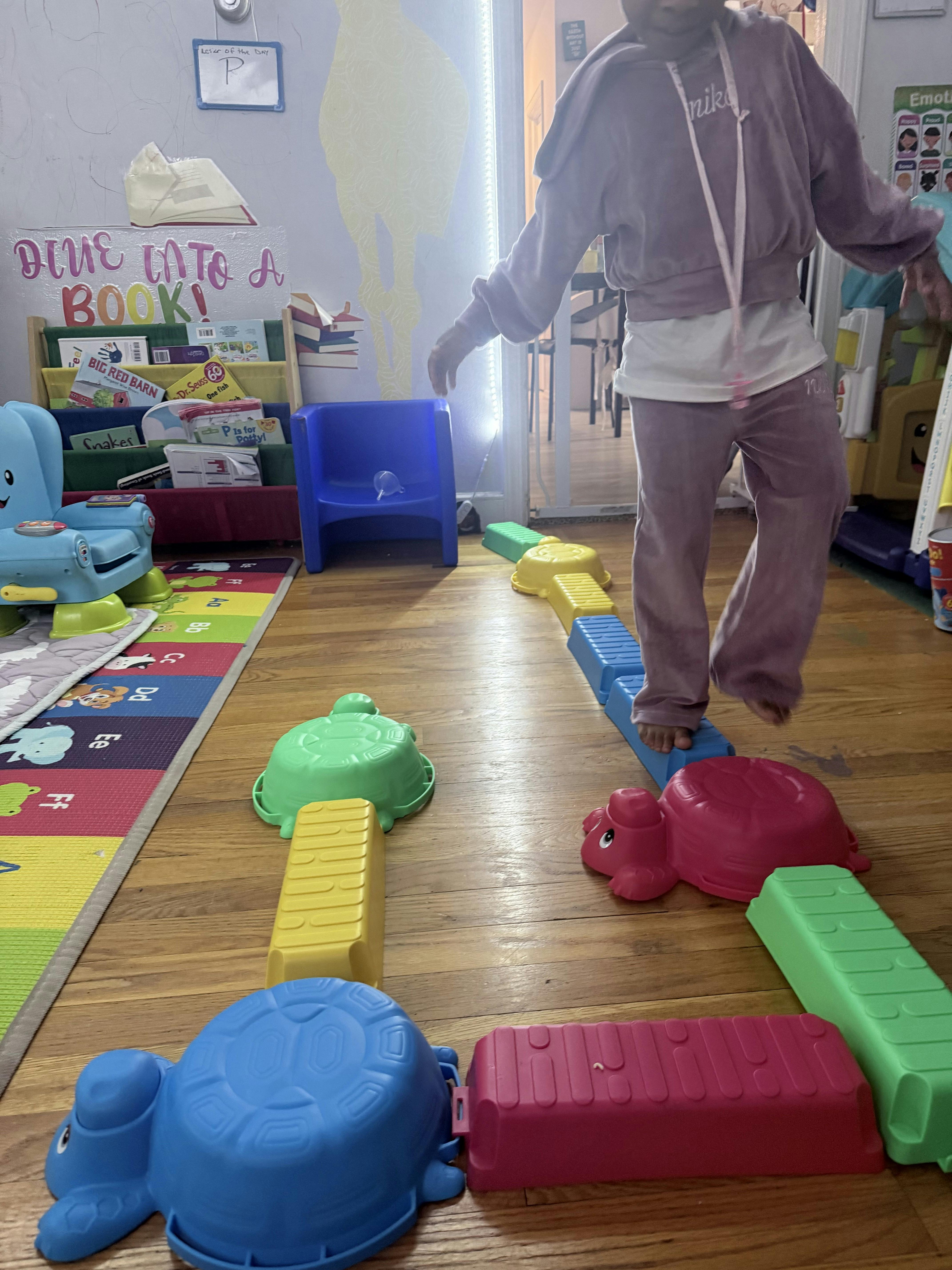 Child balancing on colorful plastic stepping stones shaped like turtles and blocks