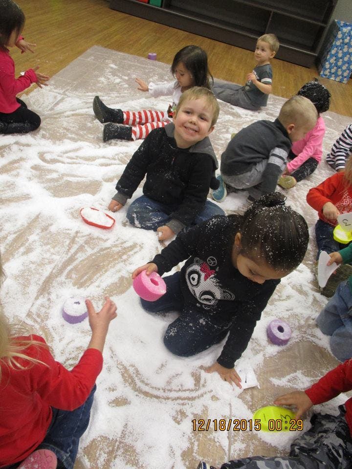Children playing with white powder and toys on the floor
