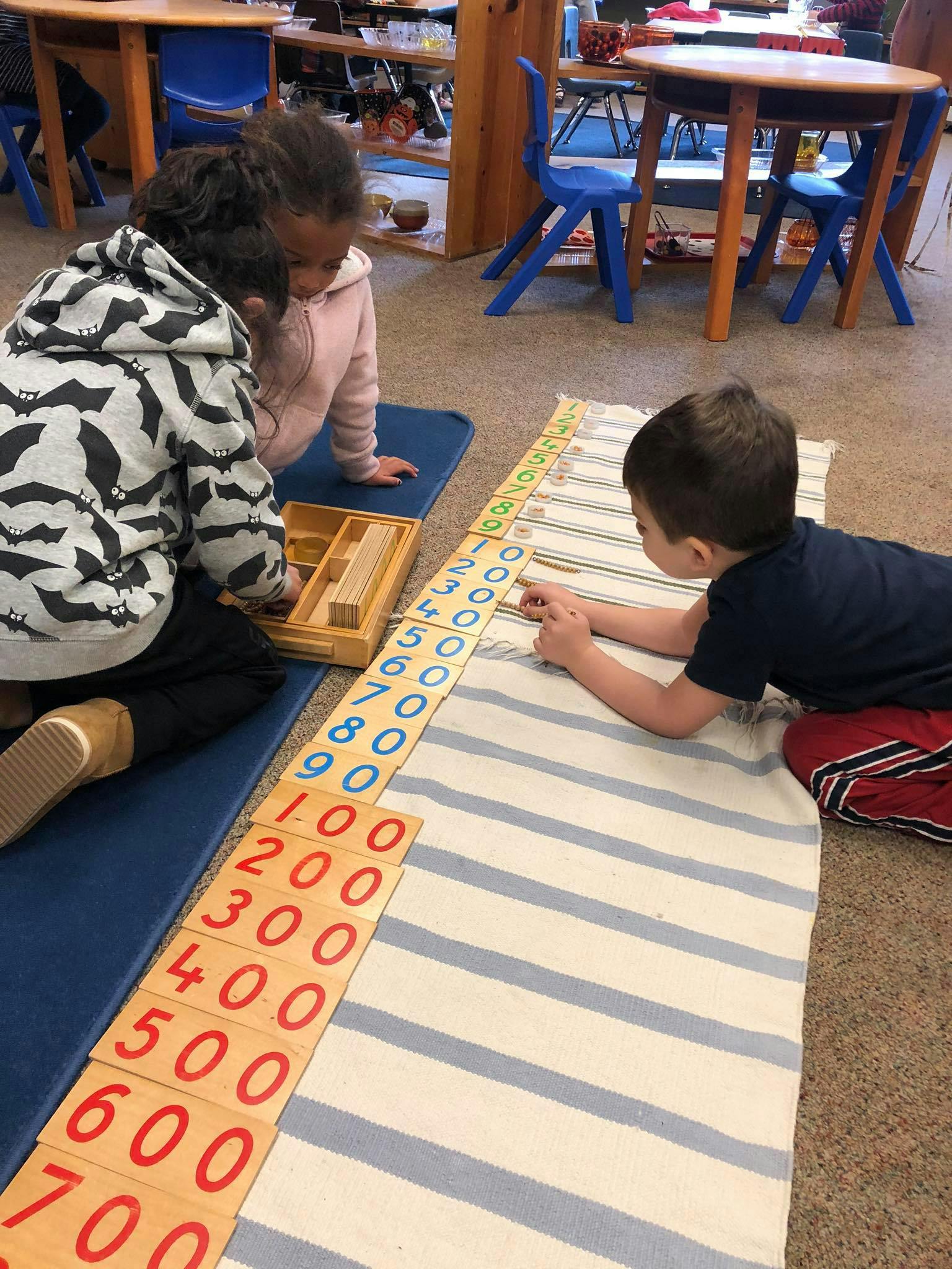 Three children on the floor playing with number blocks