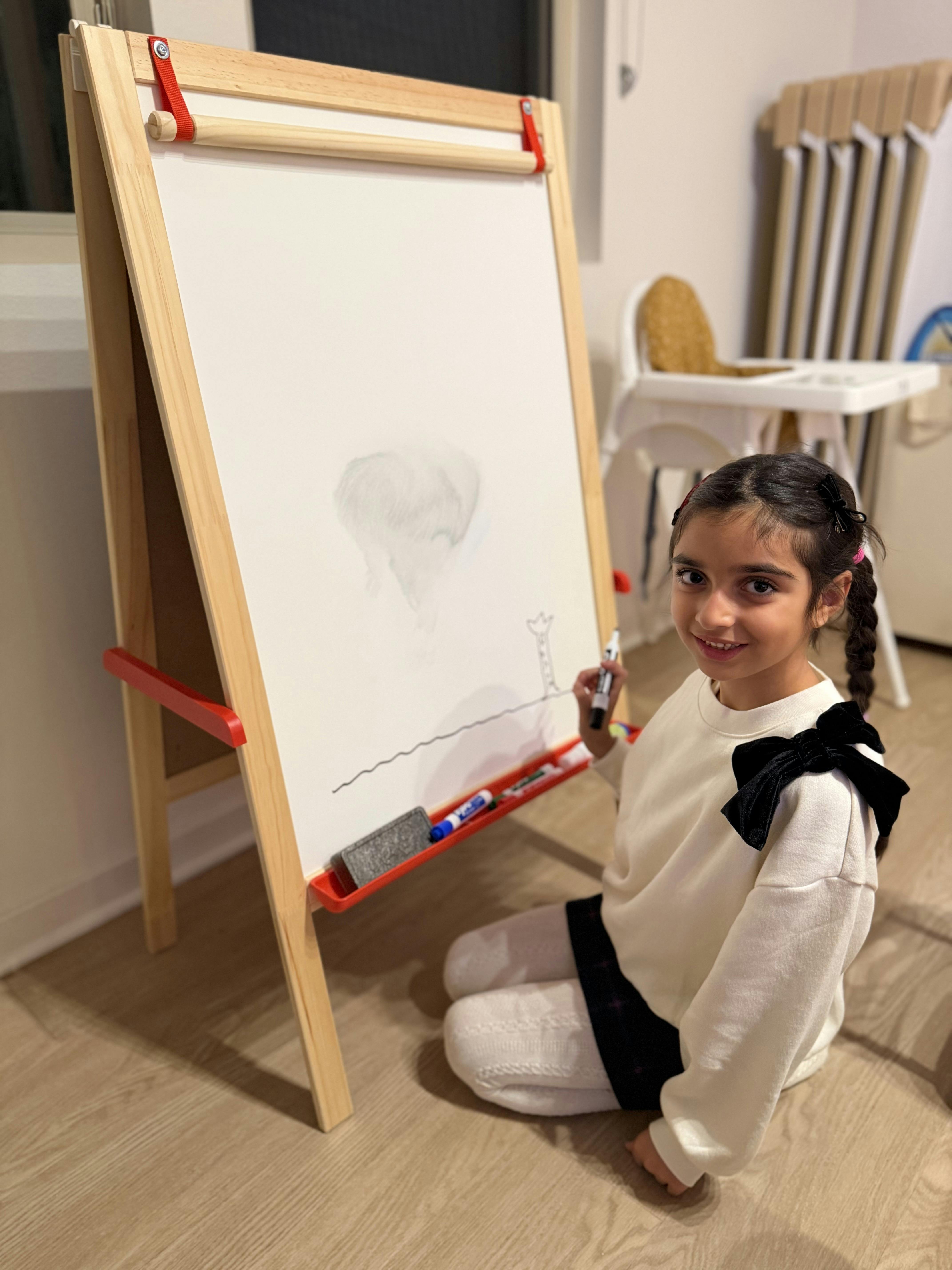 Child kneeling and drawing on an easel