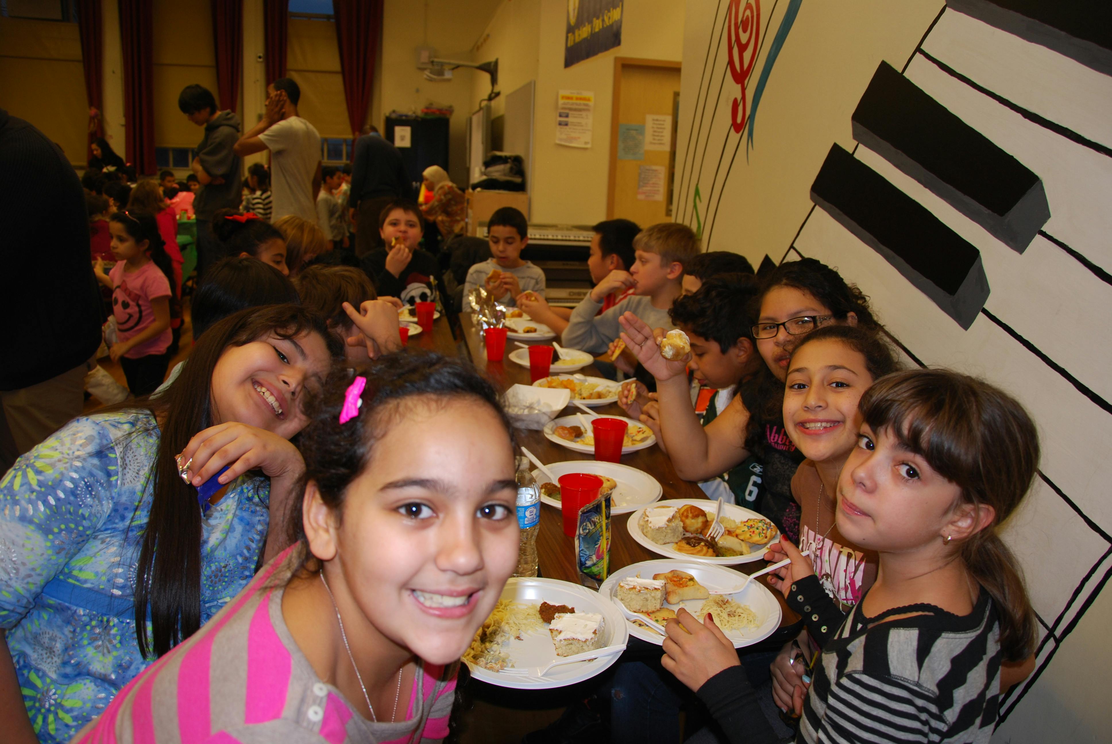 Children eating at a long table with plates of food