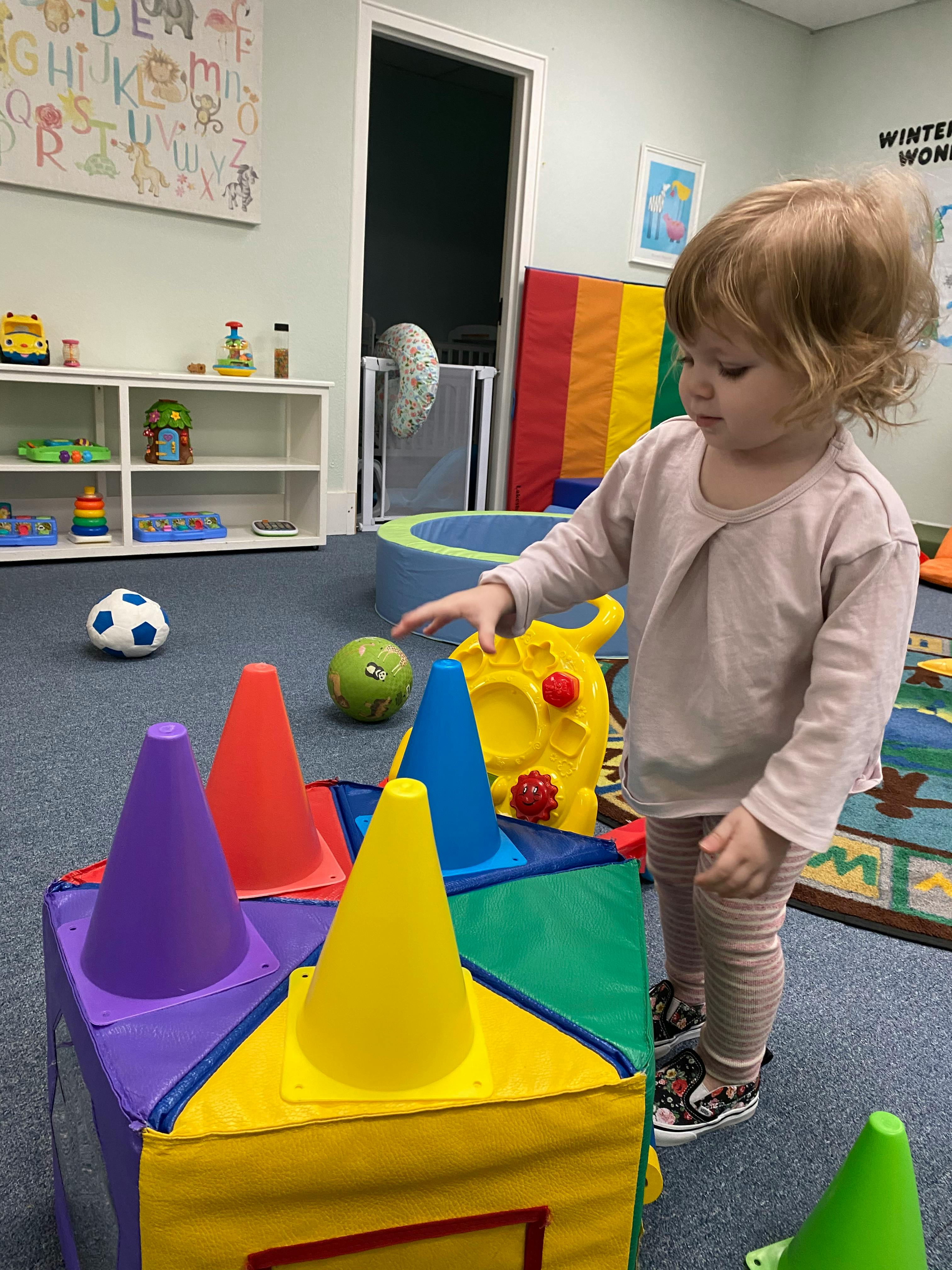 Child playing with colorful cones in a playroom