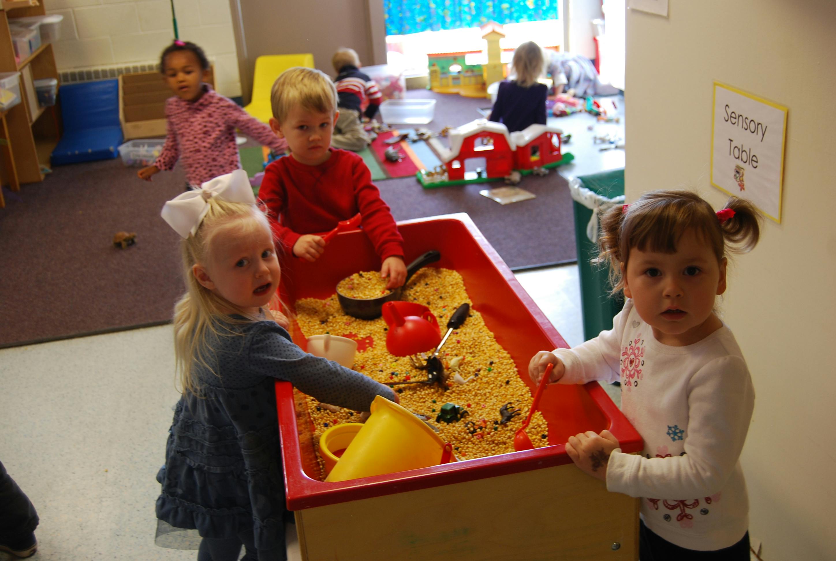 Children playing at a sensory table in a classroom