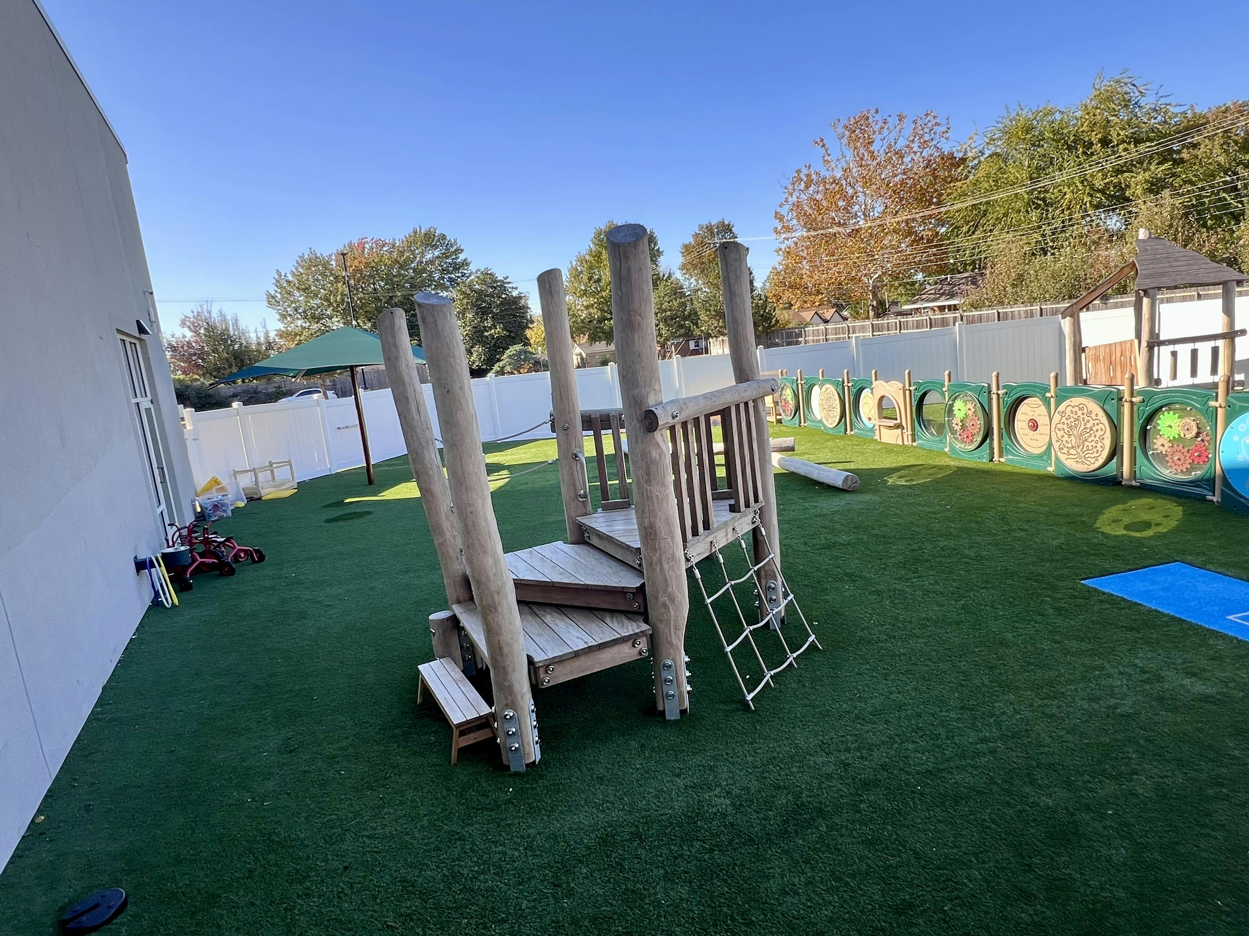 Outdoor playground with wooden climbing structure and green turf