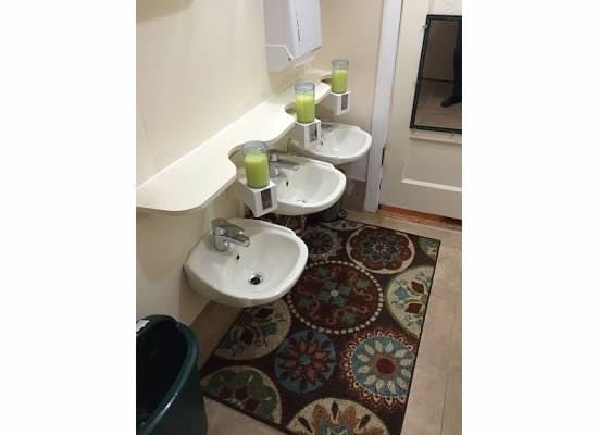 Three small sinks with soap dispensers in a row