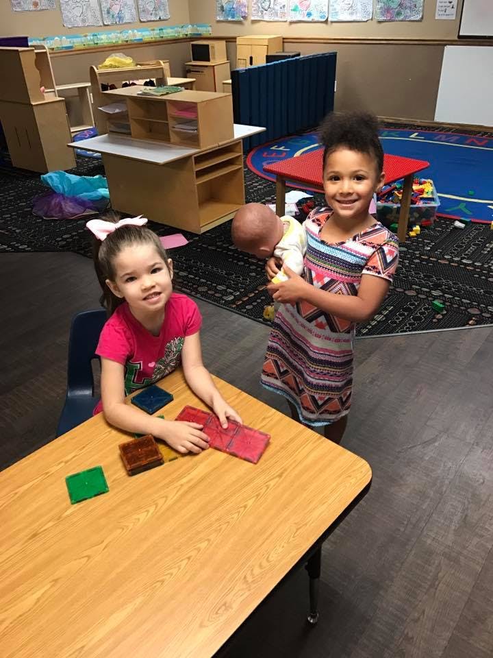 Child at table with blocks, child holding doll