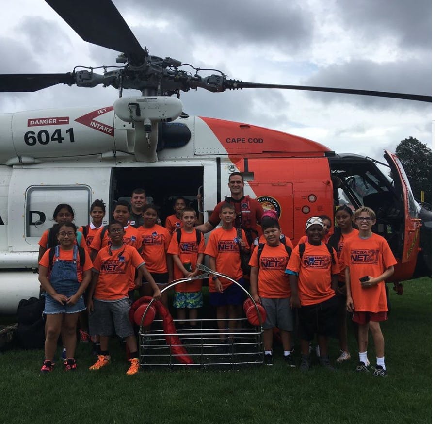Group of children and adults standing in front of a helicopter