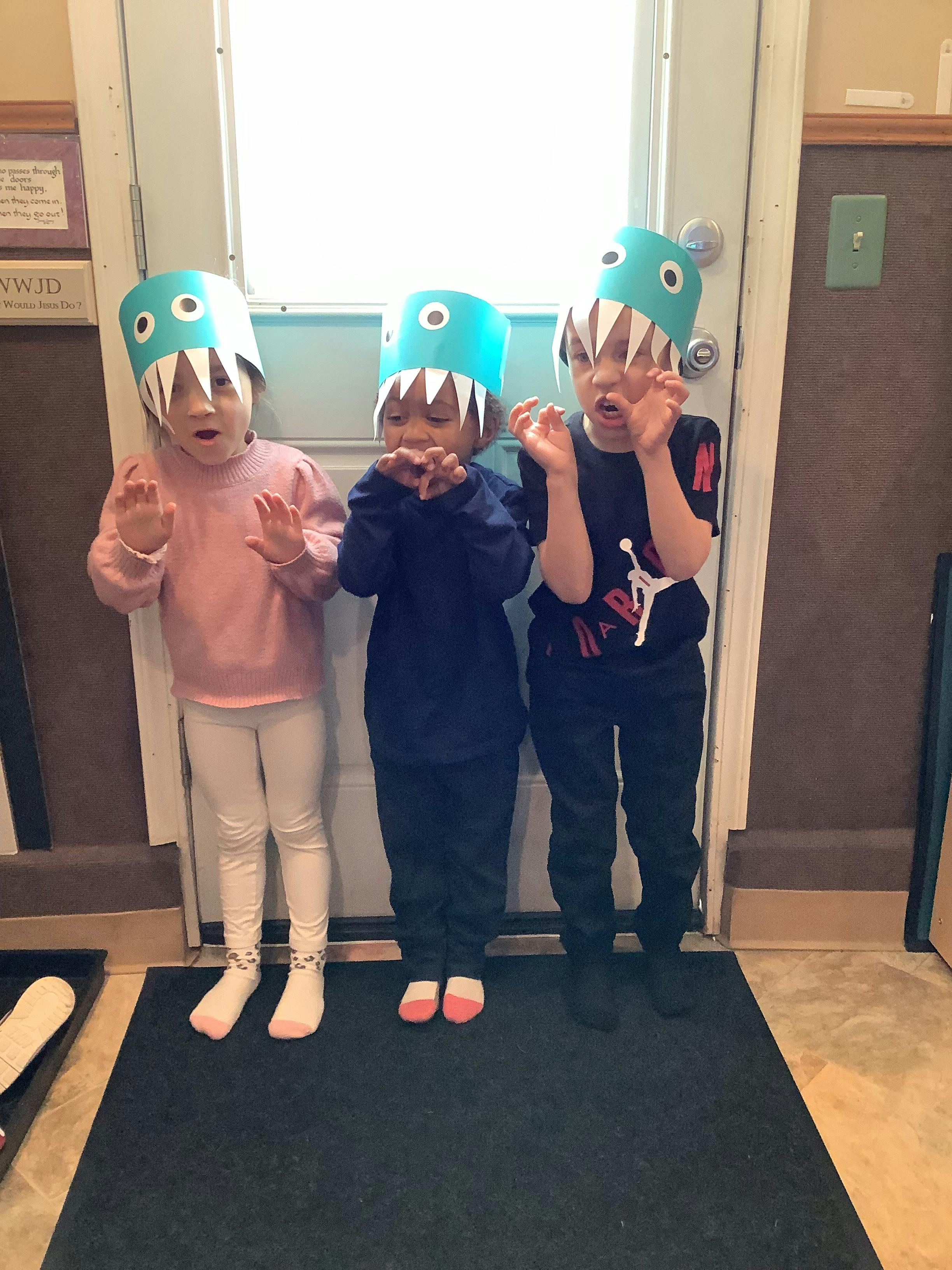Three children wearing monster hats and making monster poses