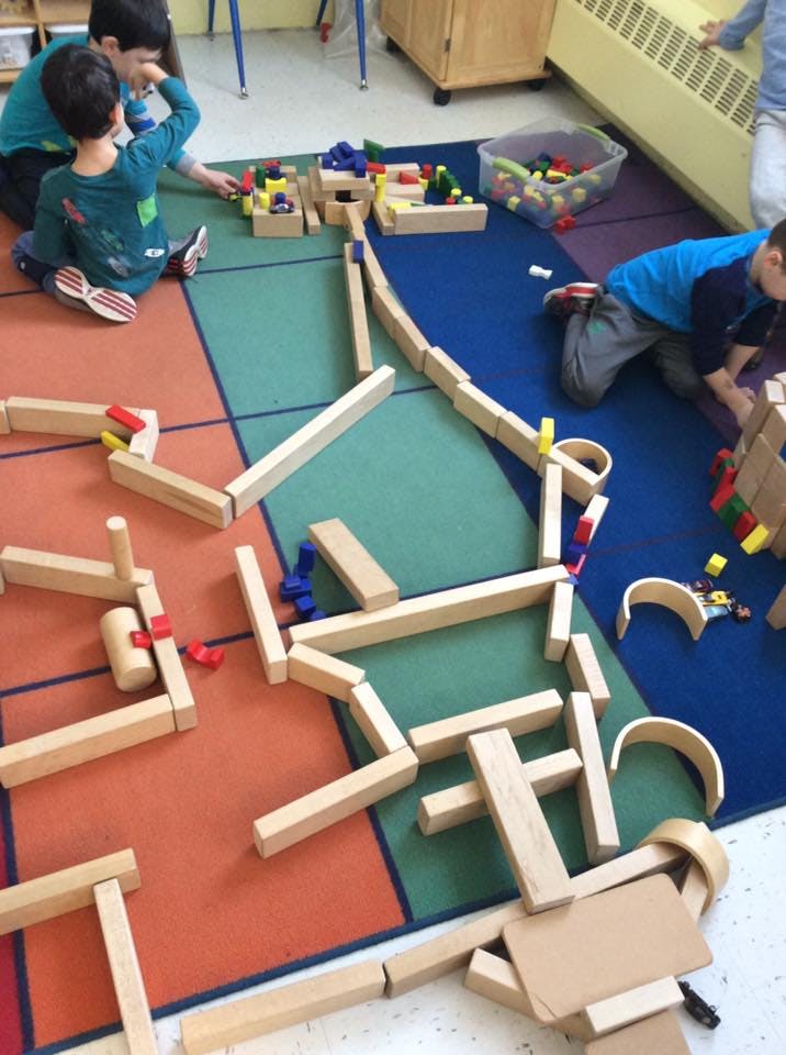 Children playing with wooden blocks on a colorful rug