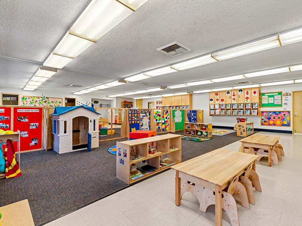A colorful classroom with play areas, child-sized tables, and learning materials