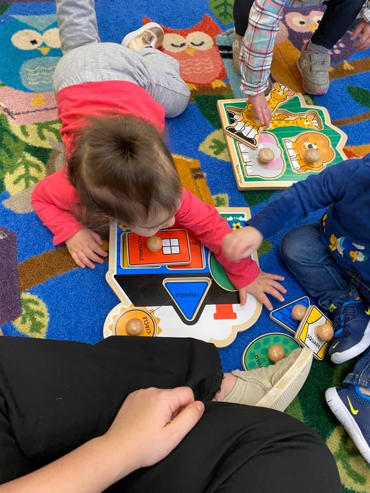 Child playing with a shape puzzle on a colorful rug