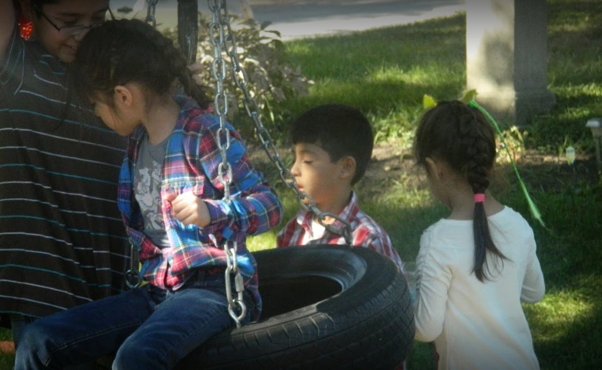 Three children around a tire swing