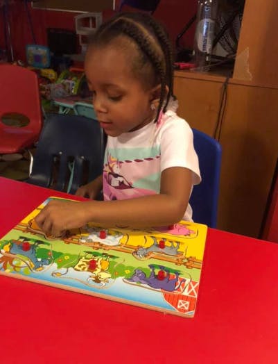 Child playing with a colorful peg puzzle on a red table