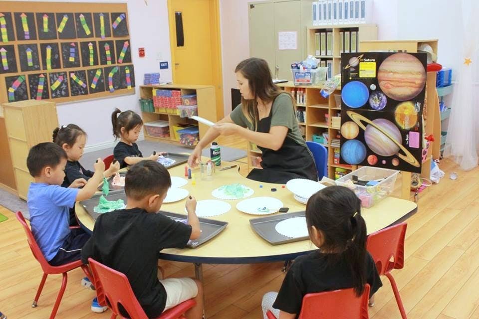 Adult and children doing an art activity in a classroom