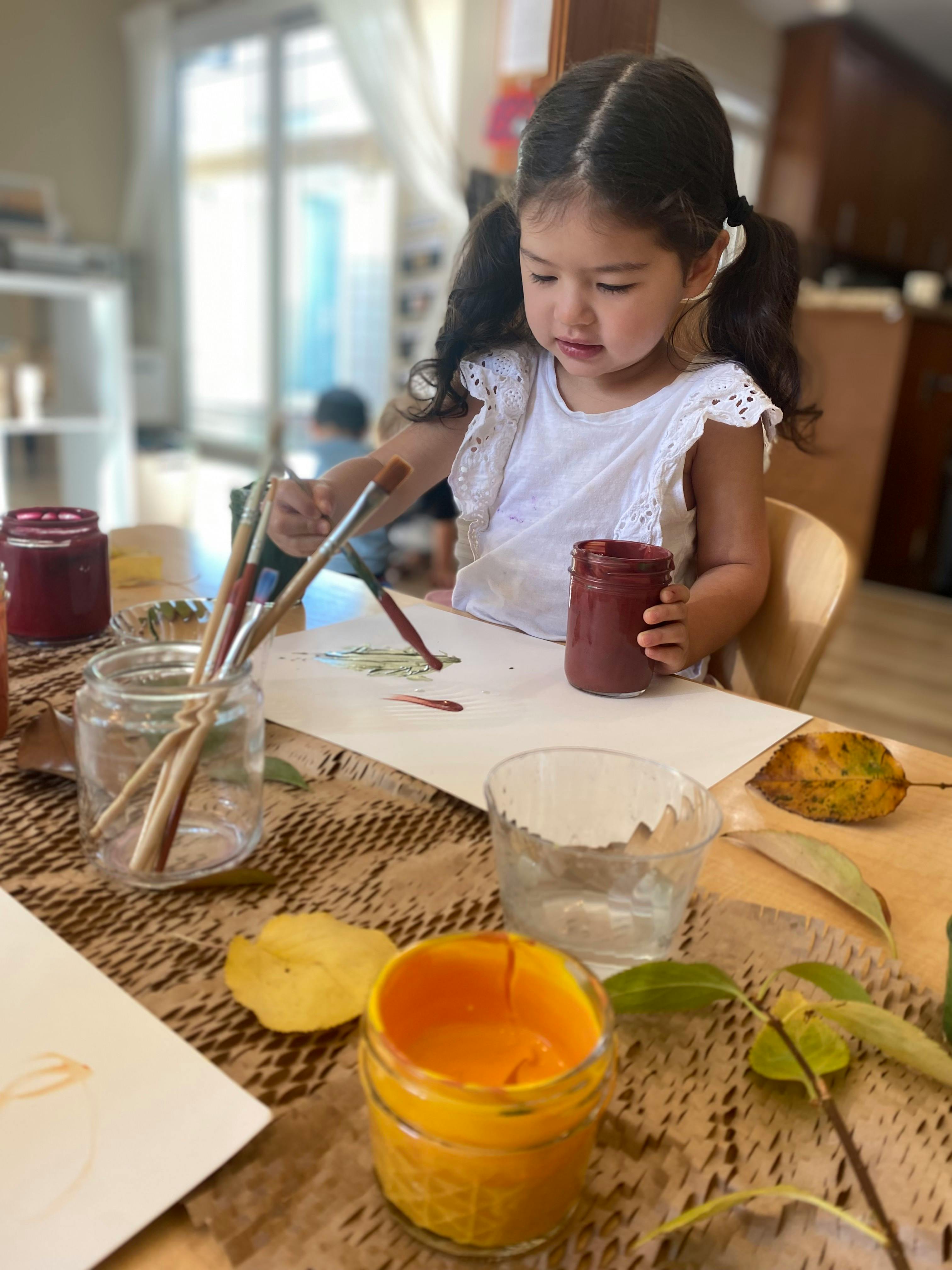 Child painting with brushes and jars of paint