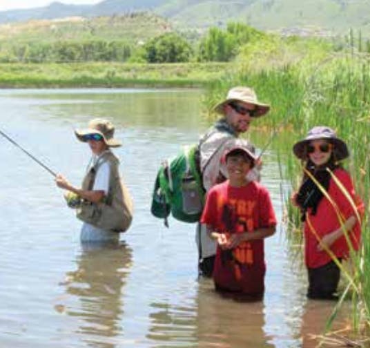 Three people and one child standing in water, fishing