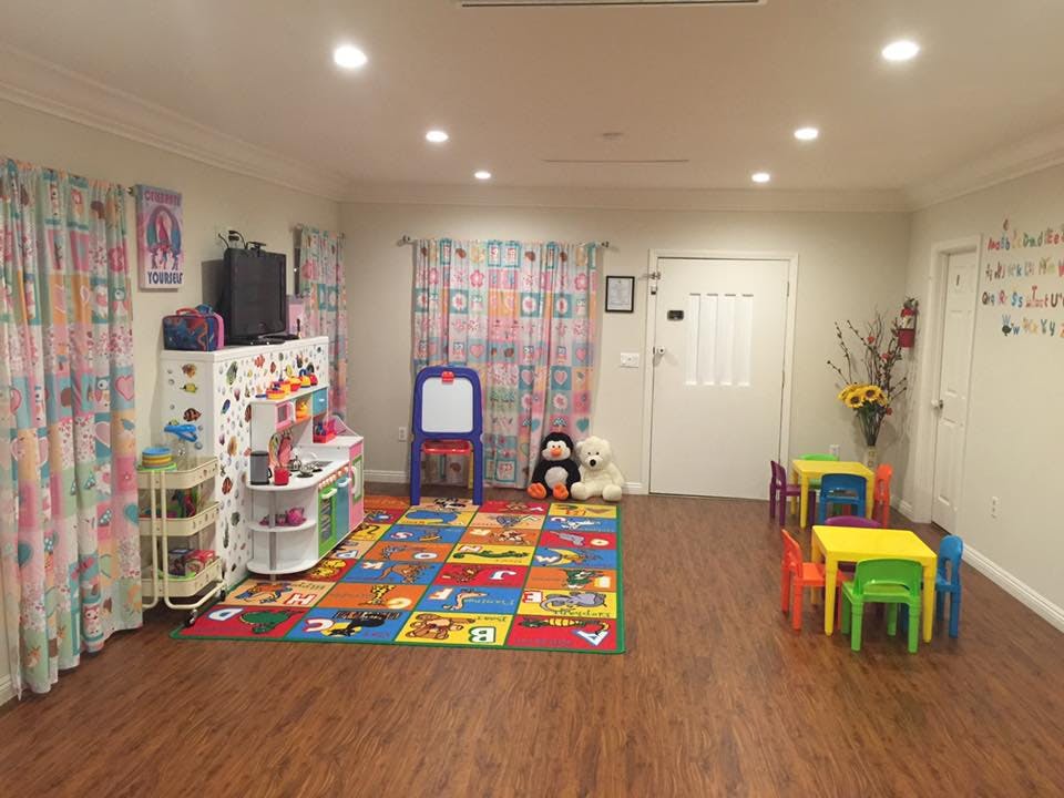 Playroom with colorful rug, small tables and chairs, and toy kitchen