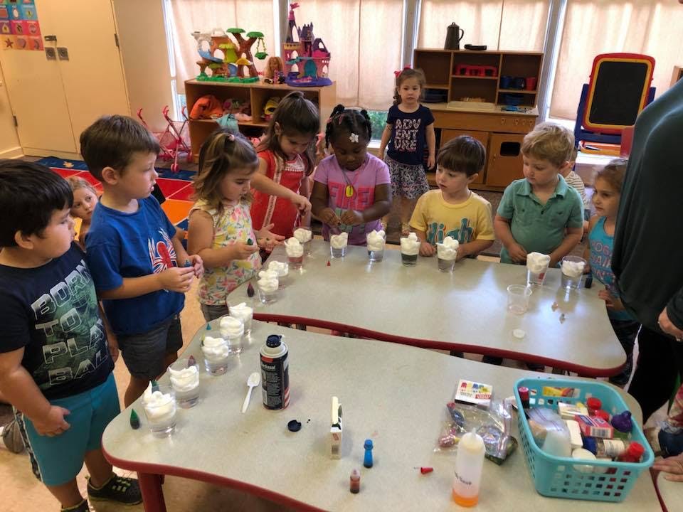 Children gathered around tables with cups of white foam