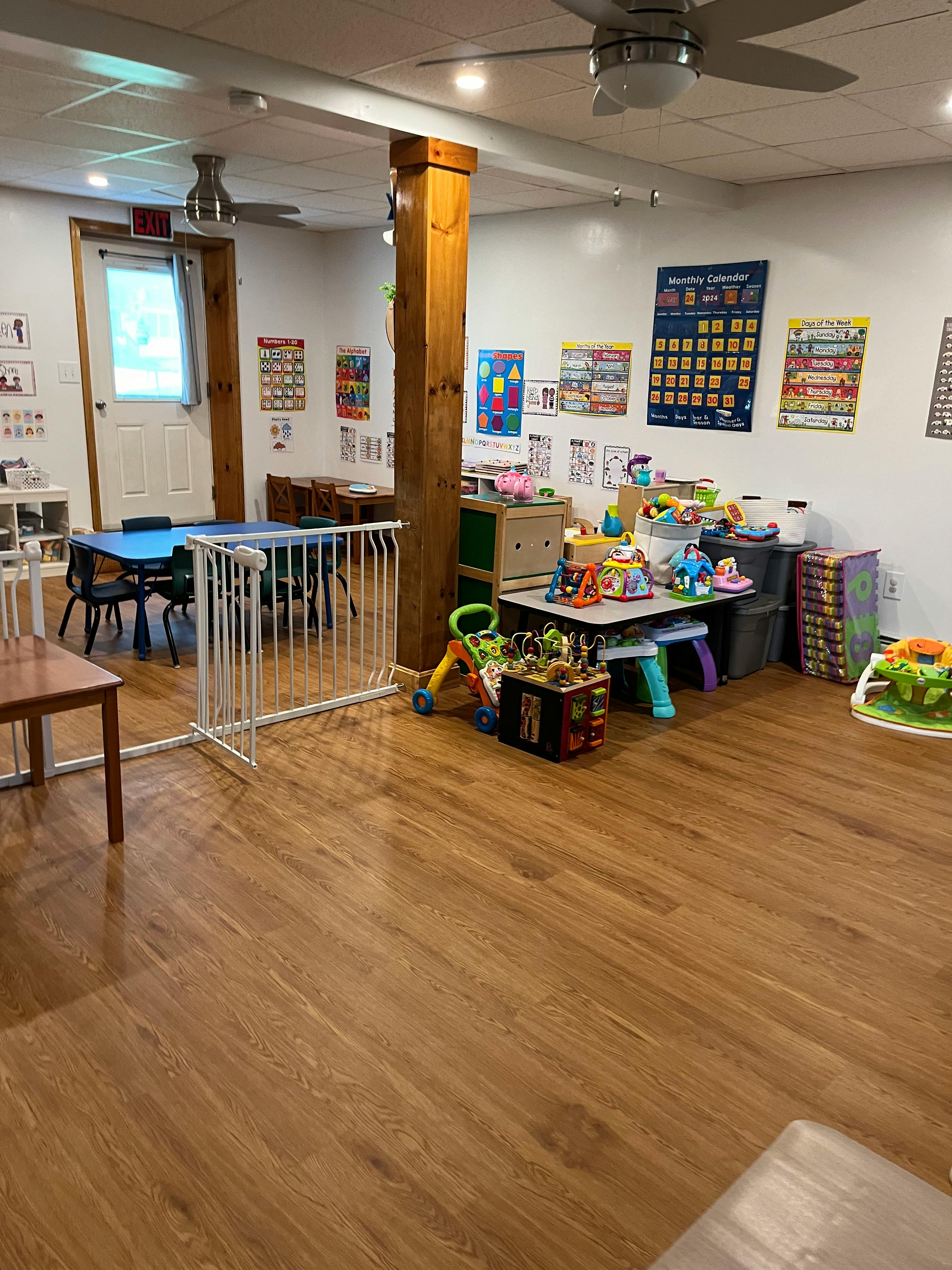 Playroom with tables, chairs, toys, and a baby gate