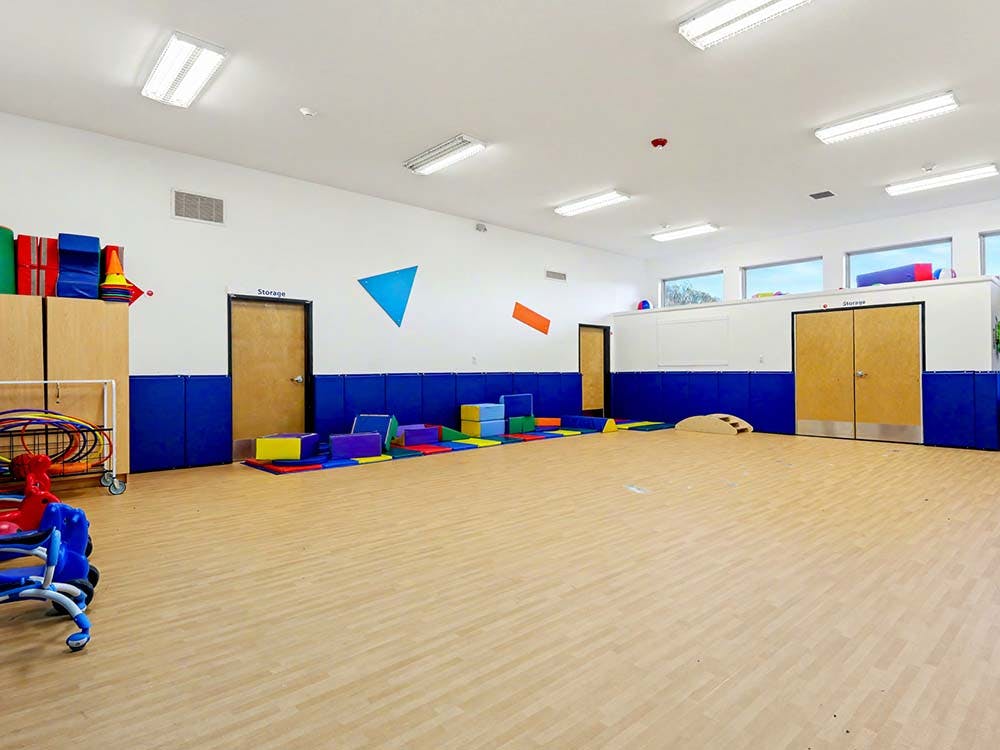 Empty colorful playroom with soft play shapes on the floor and hoops in a storage cart