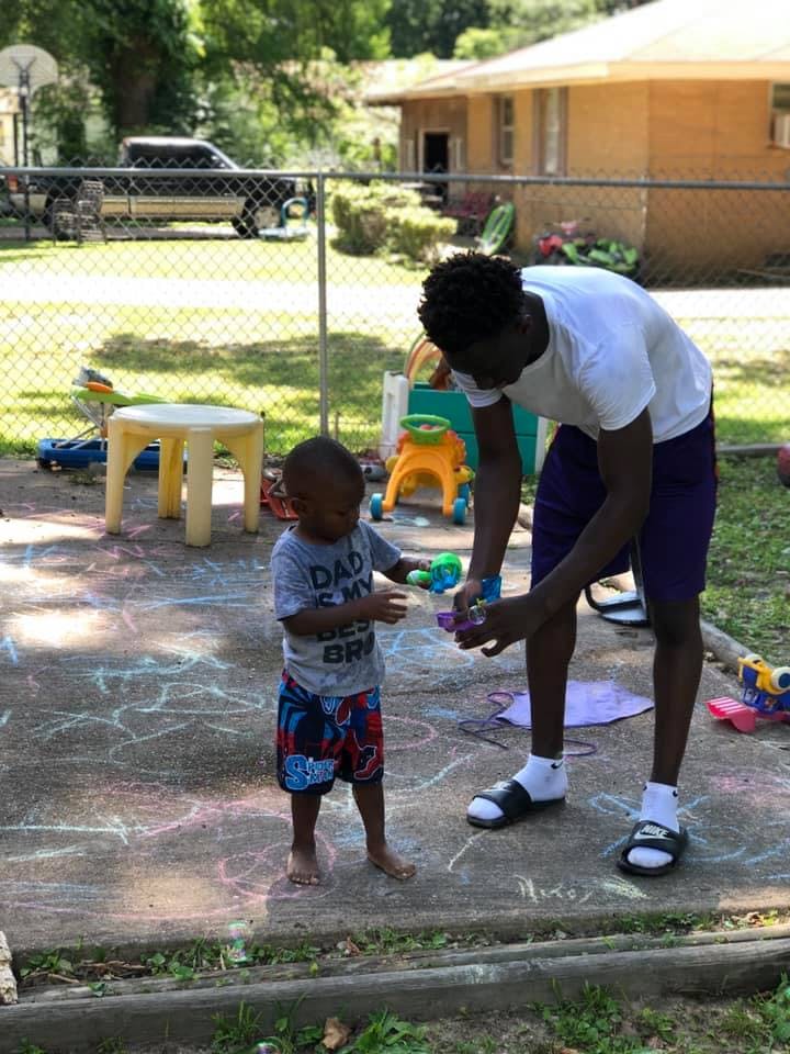 Person bending over to hand a toy to a child