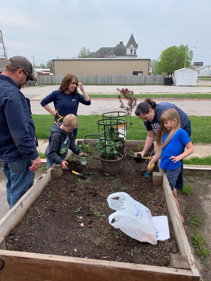 Adults and children planting in a raised garden bed