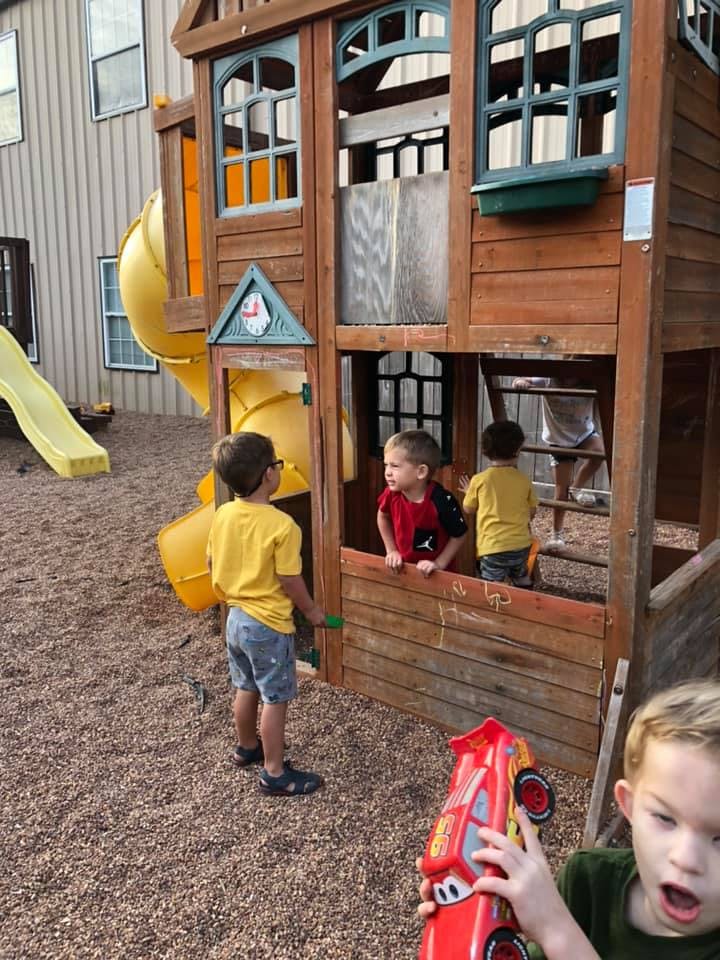 Children playing on a wooden playset with slides