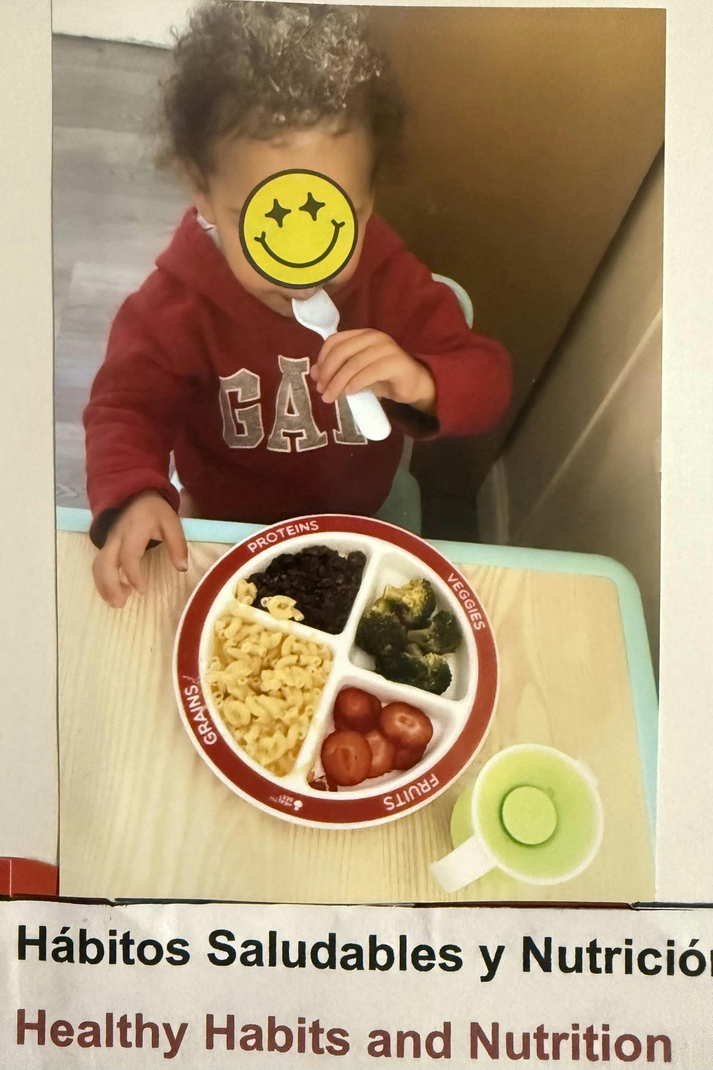 Child in a red shirt with a divided plate of food and a cup